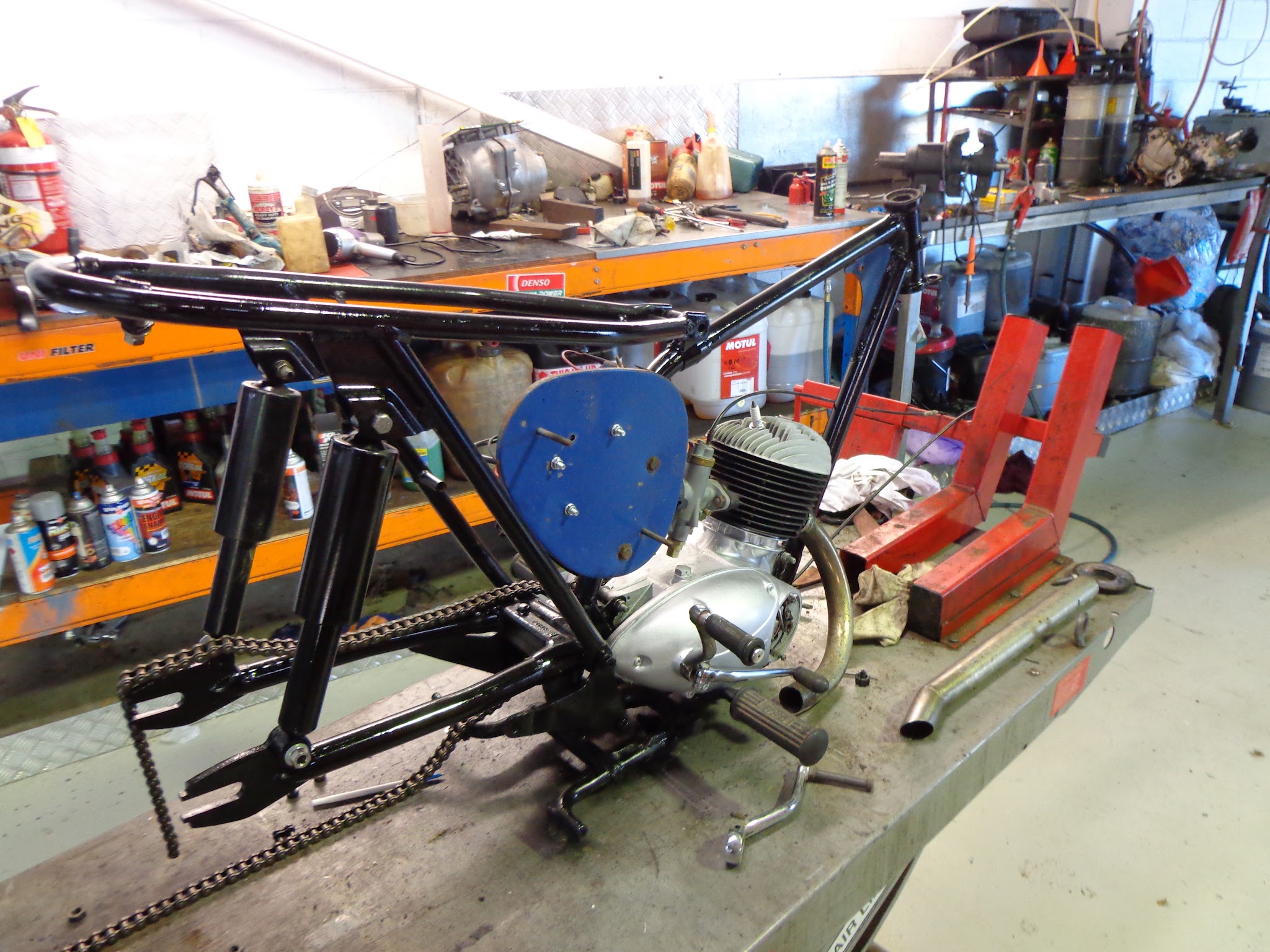 A freshly painted gloss black motorcycle frame with a rebuilt engine fitted back into it